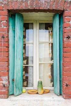 Window of a farmhouse with wooden balconies and red brick frame.