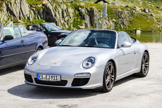 GOTTHARD PASS, SWITZERLAND - AUGUST 5, 2014: Silver supercar Porsche 991 911 at the high mountain Alpine road.