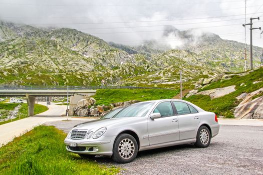 GOTTHARD PASS, SWITZERLAND - AUGUST 5, 2014: Motor car Mercedes Benz W211 E-class at the high Alpine mountain road.