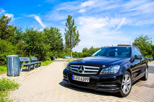 BRANDENBURG, GERMANY - JULY 20, 2014: Motor car Mercedes-Benz W204 C180 at the parking near the interurban freeway.