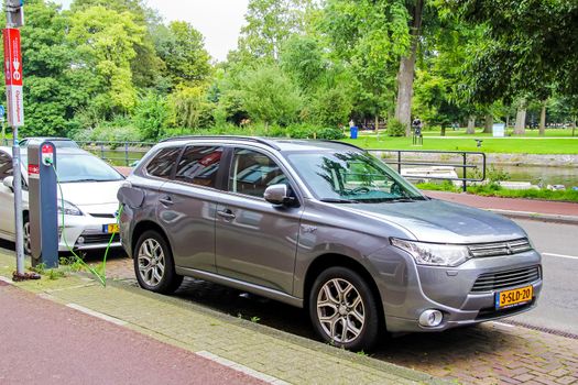 AMSTERDAM, NETHERLANDS - AUGUST 10, 2014: Motor car Mitsubishi Outlander P-HEV charging at the city street.