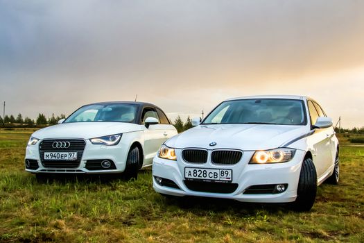 NOVYY URENGOY, RUSSIA - AUGUST 21, 2015: Motor cars Audi A1 and BMW E90 318i at the countryside.