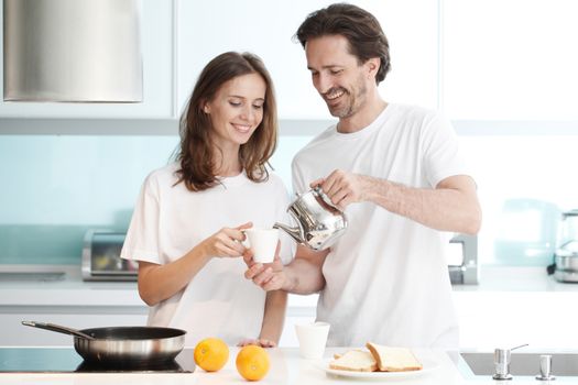 Happy couple cooking breakfast together in the kitchen