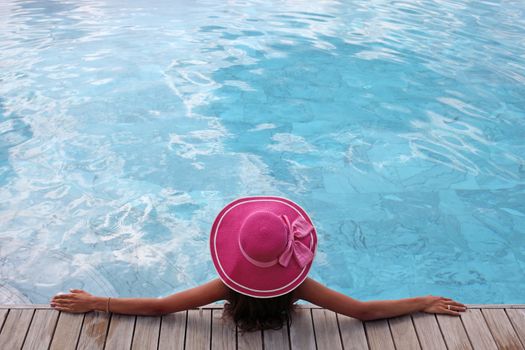 Beautiful woman relaxing at swimming pool at tourist resort