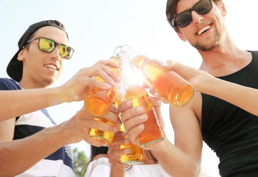 Happy young friends drinking beer outdoors