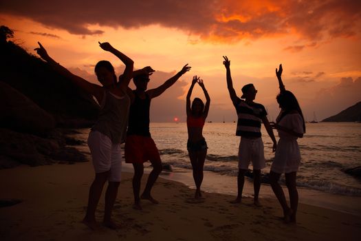 Group of people partying on beach at sunset