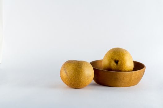 Asian pears and rustic wooden bowl on white background