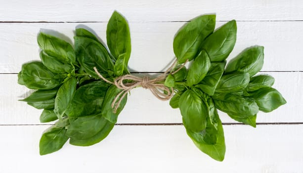 Fresh basil tied with jute on rustic wood background