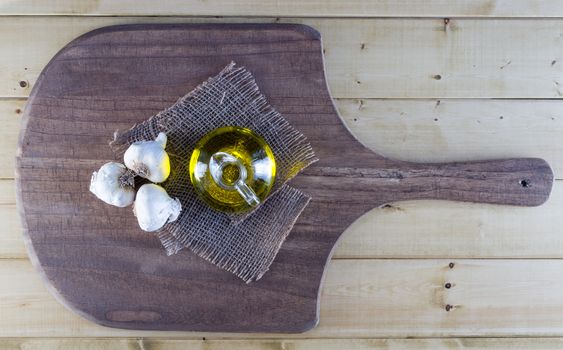 Fresh garlic bulbs and olive oil on rustic board