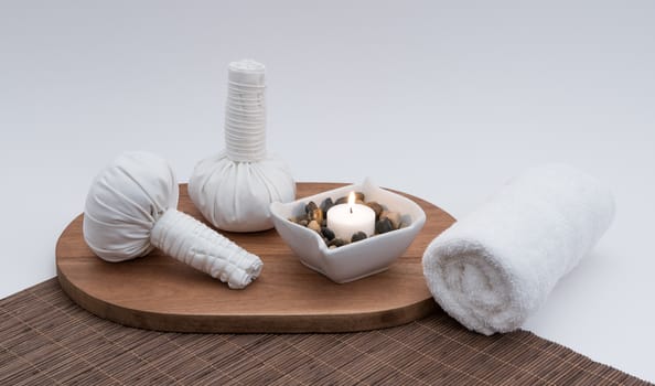 Thai herbal massage balls with lit candle and rolled white spa towel