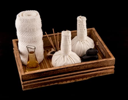 Thai herbal massage balls with massage oil and towel in wooden tray