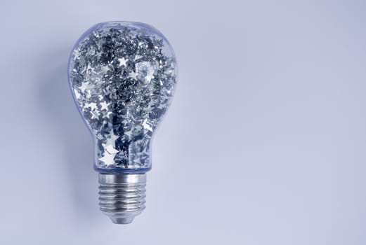 Lightbulb filled with shiny silver stars, on white background