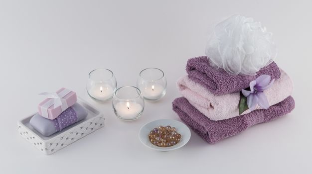 Luxury soap and aromatic bath oil beads with spa towels and lit candles