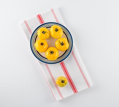 Yellow heirloom tomatoes on stoneware plate with red and white French towel