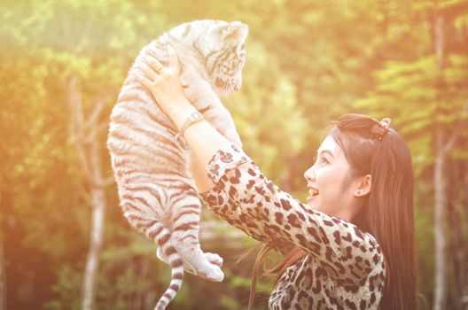 pretty women hold baby white bengal tiger with flare light