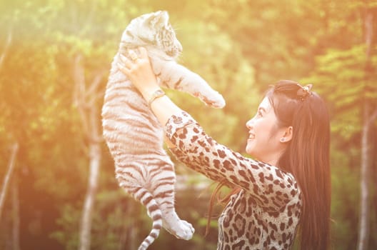 pretty women hold baby white bengal tiger with flare light