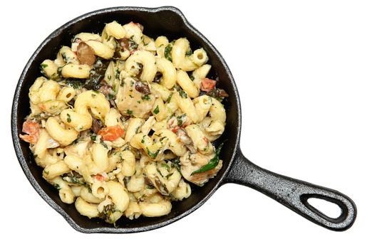 Tuscan Chicken Pasta in Cast Iron Skillet isolated over white.