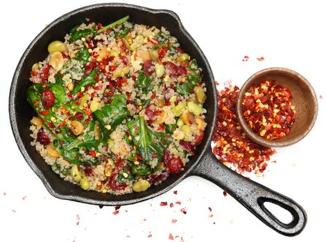 Top View Quinoa Spinach and Cranberry Salad in Cast Iron Skillet with crushed red pepper.