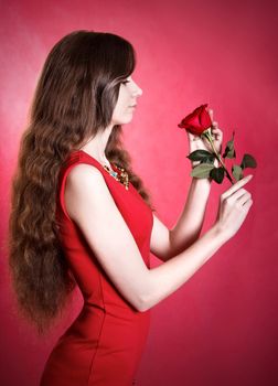 Portrait of a beautiful young woman with a red rose over pink background