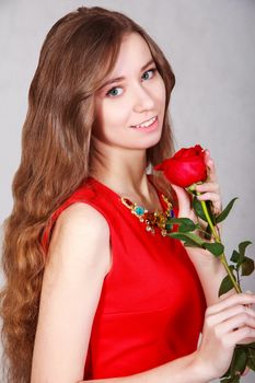 Beautiful young woman with a red rose over grey background