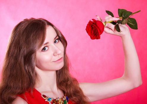 Beautiful young woman with a red rose over pink background