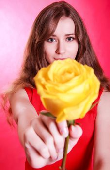 Beautiful young woman with a yellow rose over pink background