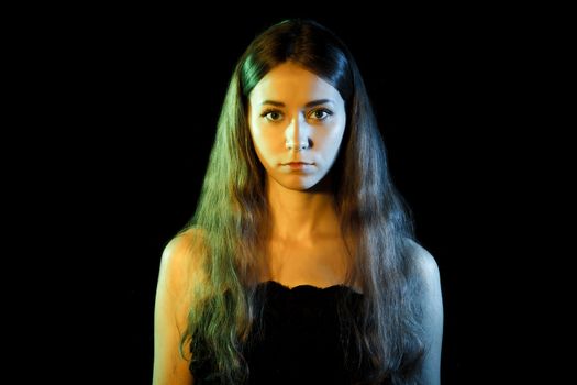 Beautiful young woman in blue and yellow lights over black background