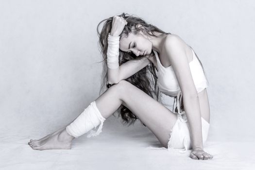 Pretty young woman with a bandage dressings on her body over grey background