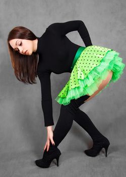 Portrait of a young attractive woman in a bright green skirt over grey background