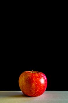 Red apple on a wooden board with black background, with empty upper half, copyspace, health related still life, simple eating, diet illustration