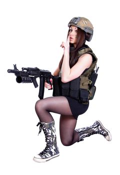 Woman in a military camouflage sitting with the assault rifle isolated over white background