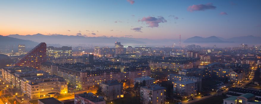 Cityscape of Slovenian capital Ljubljana at dusk. Alps mountains in background.