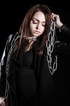 Beautiful young woman with chains over black background