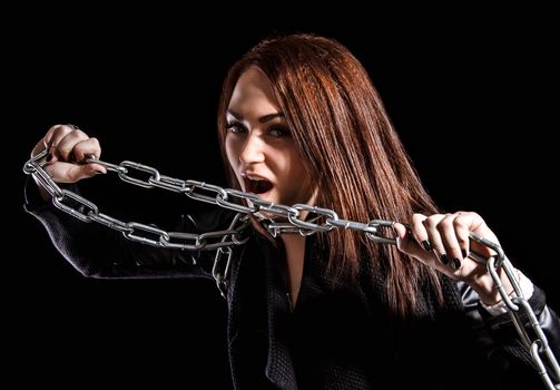 Beautiful young woman with chains over black background