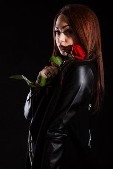 Beautiful young woman with a red rose over black background