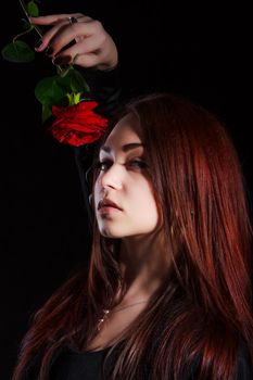 Beautiful young woman with a red rose over black background