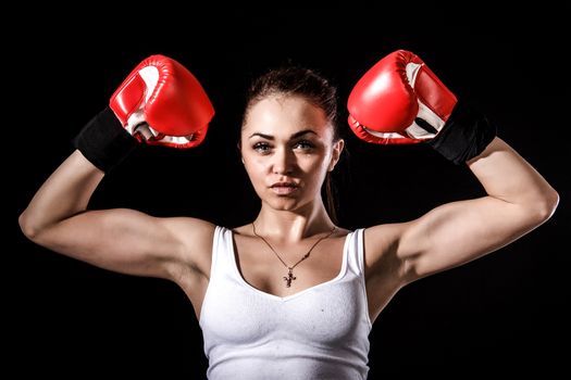 Beautiful young woman in a red boxing gloves over black background