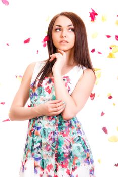 Portrait of a pretty young woman in a bright dress isolated over white background with pink and yellow falling petals