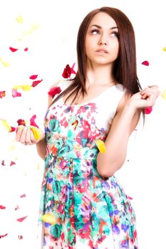 Portrait of a pretty young woman in a bright dress isolated over white background with pink and yellow falling petals