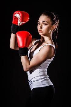 Beautiful young woman in a red boxing gloves over black background