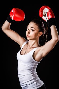 Beautiful young woman in a red boxing gloves over black background