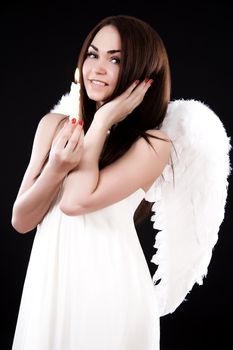 Happy young angel with a candle over black background