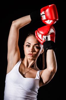 Beautiful young woman in a red boxing gloves over black background