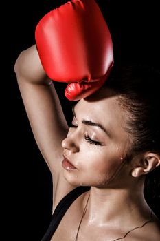 Beautiful young woman in a red boxing gloves over black background