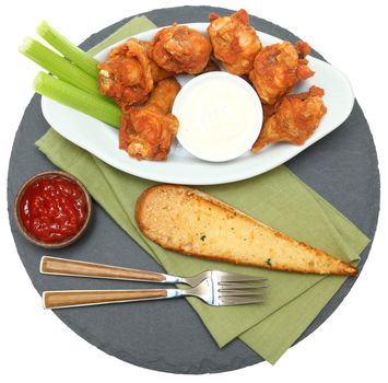 Spicy Chicken Wings with Celery Sticks and Ranch top view on slate over white.