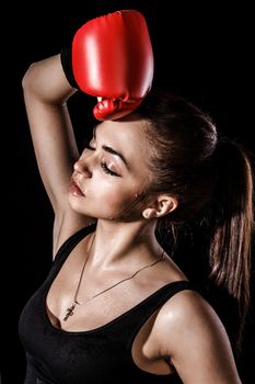 Beautiful young woman in a red boxing gloves over black background