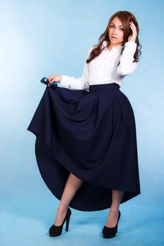 Beautiful young woman in a long dark skirt over blue background