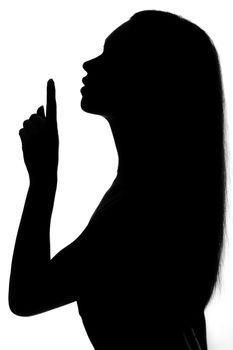 Silhouette of a woman making the silence gesture