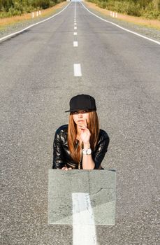 Beautiful young woman sitting on the road with a mirror