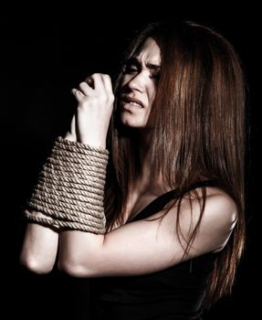 Beautiful young woman with tied arms over black background